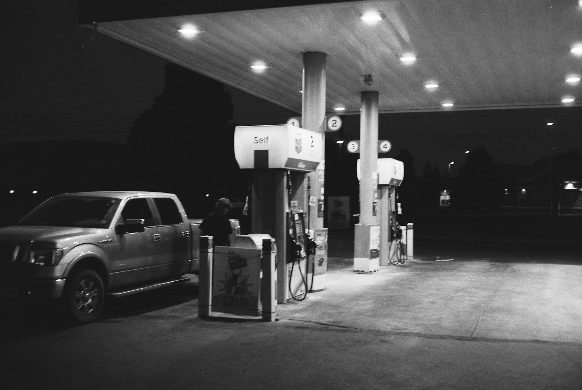 A pickup truck at a gas station at night